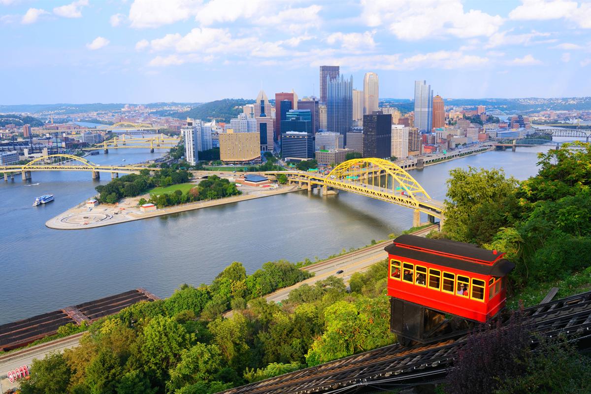 Pittsburgh skyline, yellow bridges, riverfront greenery and a red incline car