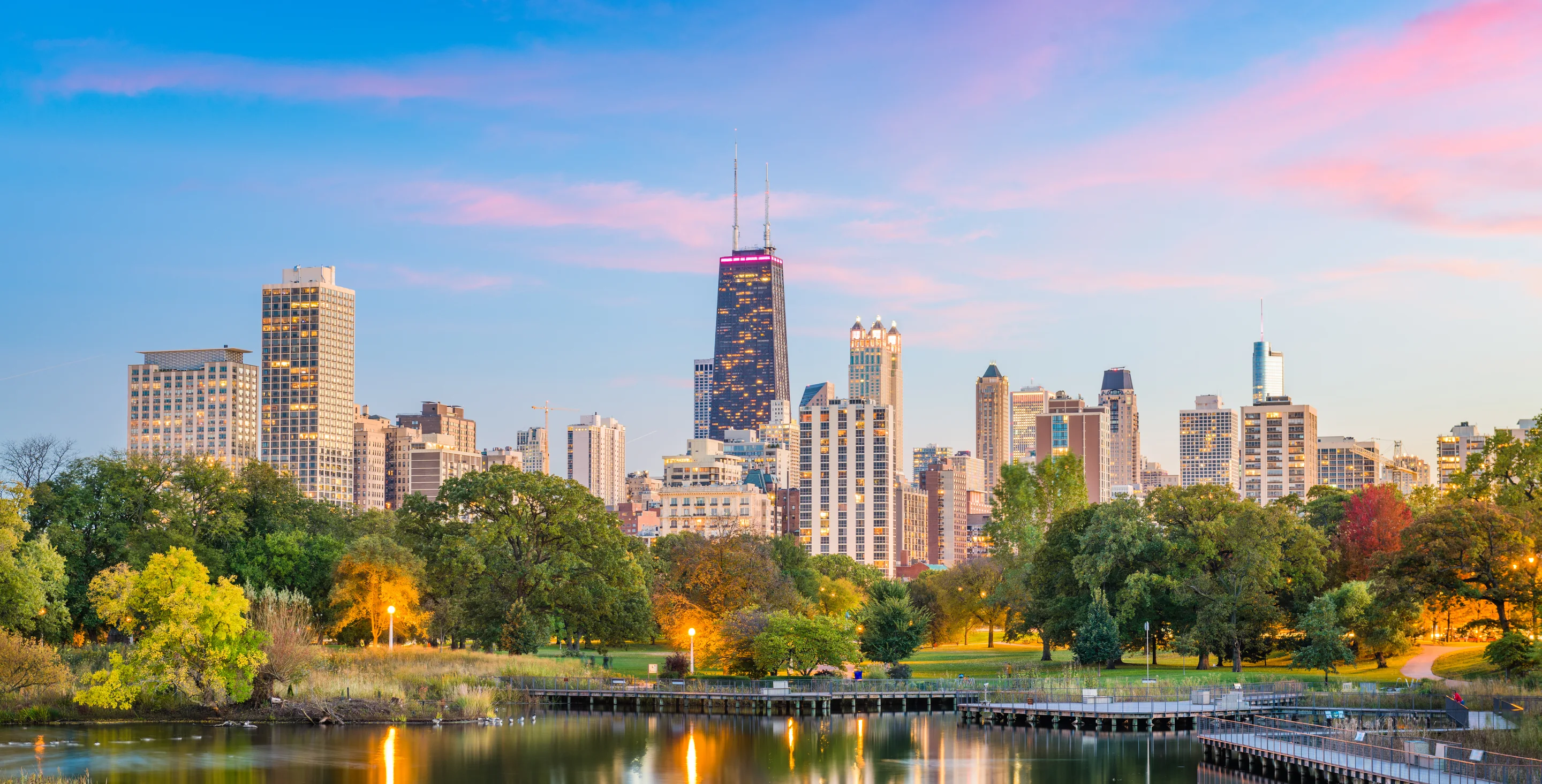 Chicago skyline beyond a tree-lined park at dusk